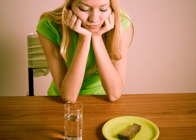 A girl is sitting in front of a glass of water and bread